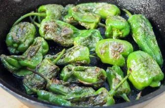 Pimientos de Padrón con sal marina sobre un plato blanco, una tapa tradicional española.