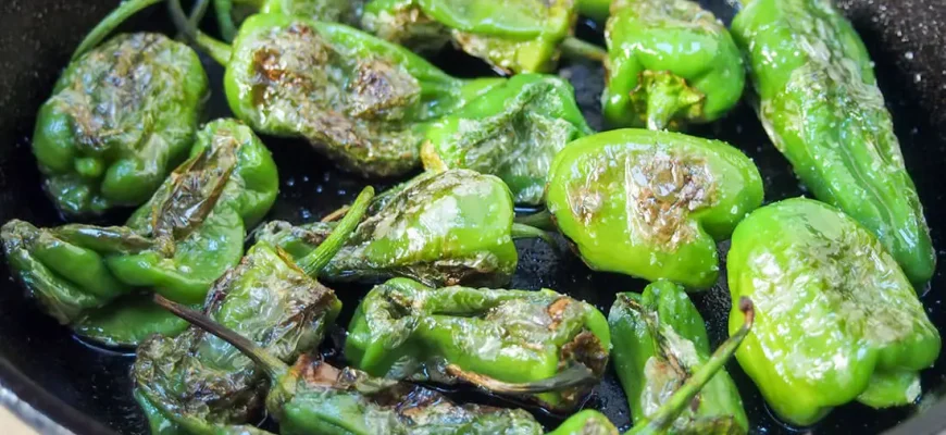 Pimientos de Padrón con sal marina sobre un plato blanco, una tapa tradicional española.