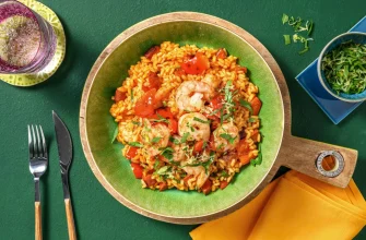 Paella de chorizo y gambas con limón y perejil en una sartén grande.