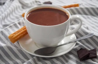 Taza de chocolate caliente español espeso y cremoso, servido con churros crujientes.