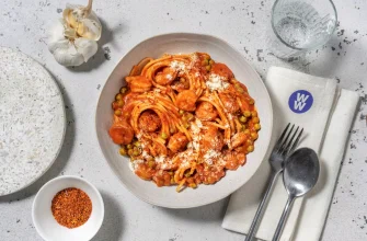 Plato de espaguetis con camarones, tomate fresco, guisantes y queso italiano rallado.