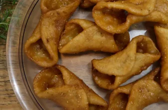 Pestiños caseros tradicionales dorados y cubiertos de miel, dispuestos en un plato.